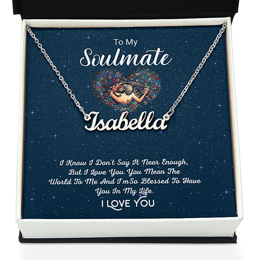 A silver nameplate necklace displayed inside a white gift box with a dark blue starry insert. The necklace has a custom nameplate reading 'Isabella' and is shown with the message 'To My Soulmate Isabella' and a romantic poem printed on the insert card.