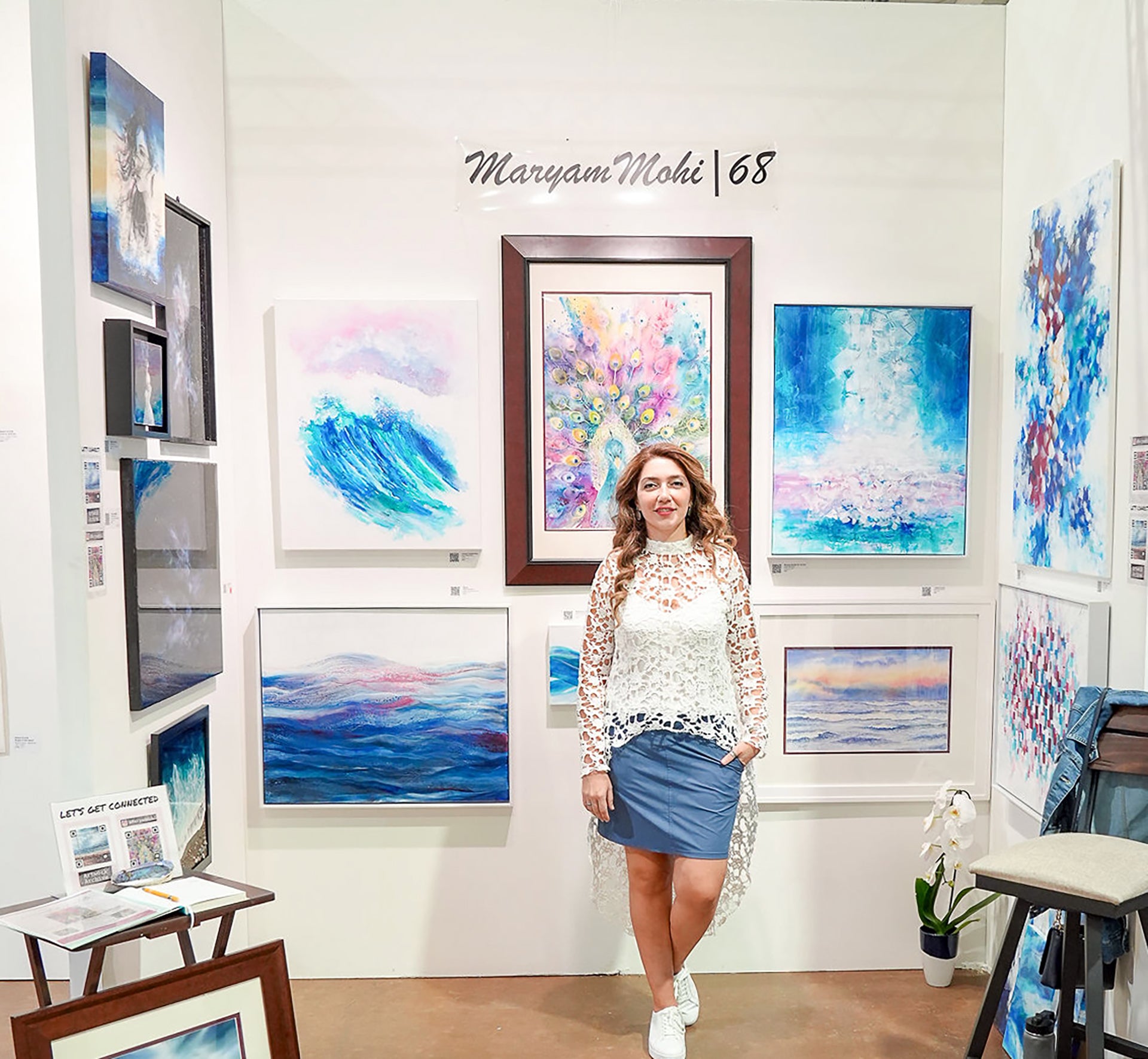 Woman standing in an art gallery surrounded by colorful paintings.